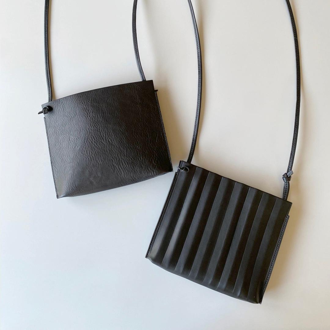ジグザグとフラットの両面楽しめる、２つの黒い革のスマホポシェット／2点限定